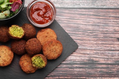 Photo of Delicious vegan cutlets and falafel ball served with sauce on wooden table, flat lay. Space for text