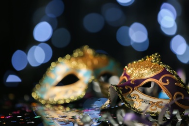 Beautiful carnival mask on table against blurred lights. Space for text