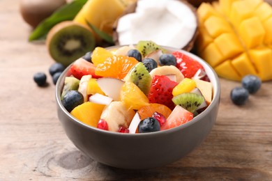 Delicious fresh fruit salad in bowl on wooden table