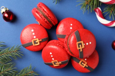 Photo of Pile of beautifully decorated Christmas macarons on blue background, flat lay