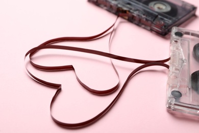 Music cassettes and hearts made of tape on pink background, closeup. Listening love songs