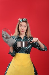 Young housewife with saucepan on red background