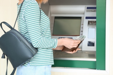 Woman with money near cash machine outdoors, closeup