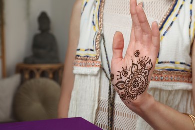 Woman with henna tattoo on palm indoors, closeup and space for text. Traditional mehndi ornament