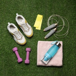 Flat lay composition with sports equipment on green grass