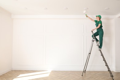 Worker painting ceiling with white dye indoors, space for text