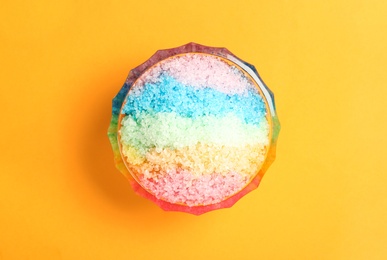Rainbow shaving ice in glass dessert bowl on orange background, top view