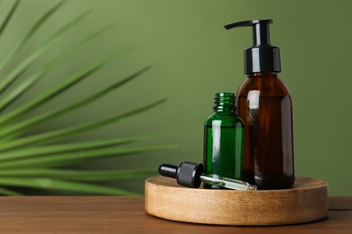 Bottles of hydrophilic oil on wooden table against green background. Space for text