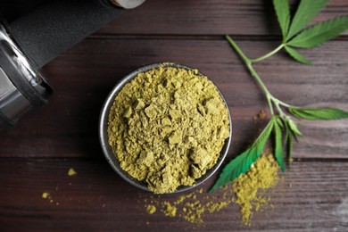 Hemp protein powder, fresh leaves and dumbbell on wooden table, flat lay