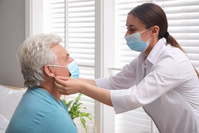 Doctor putting protective mask on senior man at nursing home