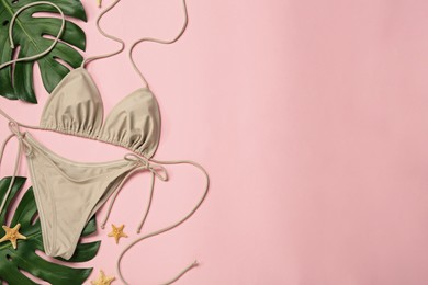 Stylish bikini, tropical leaves and starfishes on pink background, flat lay. Space for text