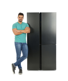 Young man near refrigerator on white background
