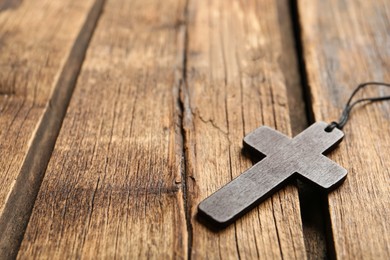 Christian cross on wooden table, closeup. Space for text