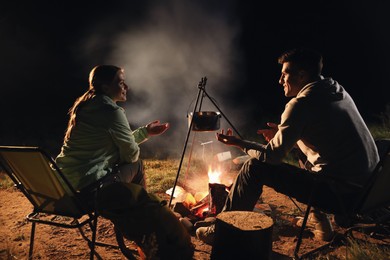 Couple near bonfire outdoors in evening. Camping season