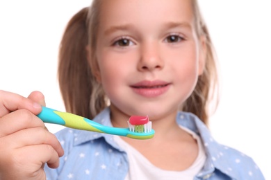 Little girl holding toothbrush with paste on white background, closeup