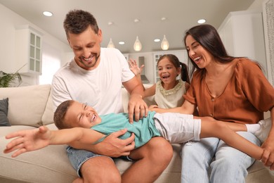Happy family with children having fun on sofa at home