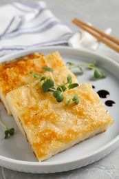 Delicious turnip cake with microgreens served on grey table, closeup