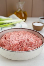 Photo of Bowl of raw fresh minced meat on white wooden table, closeup