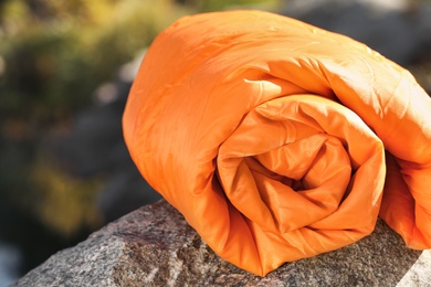Orange sleeping bag on rock outdoors. Camping equipment