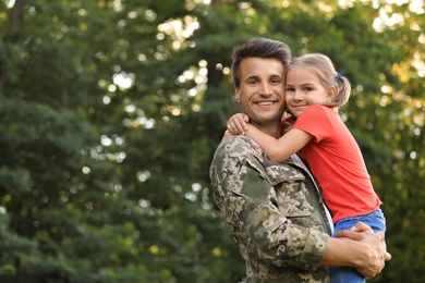 Father in military uniform holding his little daughter at green park