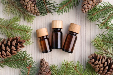 Flat lay composition with pine essential oil, cones and branches on wooden table