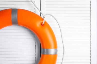 Orange lifebuoy on white wooden background, space for text. Rescue equipment