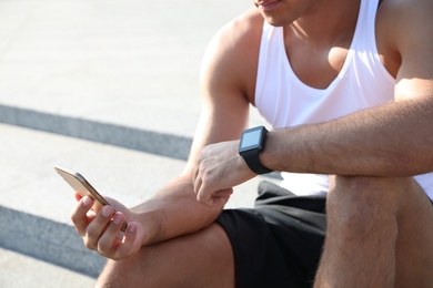 Man with fitness tracker and smartphone after training outdoors, closeup