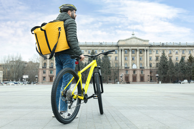 Courier with thermo bag and bicycle on city street. Food delivery service