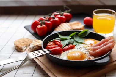 Delicious fried eggs with spinach, tomatoes and ham served on table