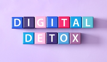 Photo of Color cubes with words DIGITAL DETOX on violet background, flat lay