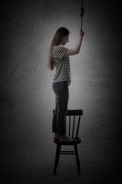 Depressed woman with rope noose standing on chair against grey background. Suicide concept