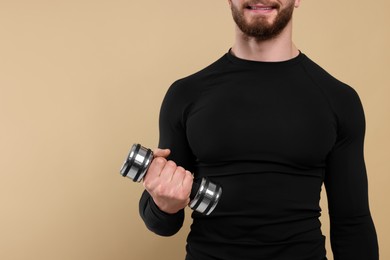 Photo of Sportsman exercising with dumbbell on brown background, closeup. Space for text
