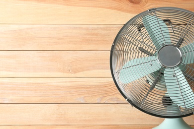 Photo of Electric fan near wooden wall, space copy text. Summer heat