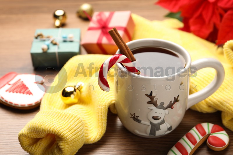 Photo of Composition with cup of hot drink and yellow sweater on wooden table, closeup