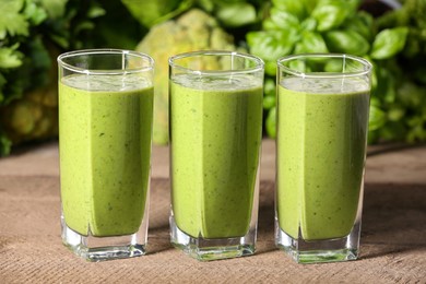 Glasses of fresh green smoothie and ingredients on wooden table