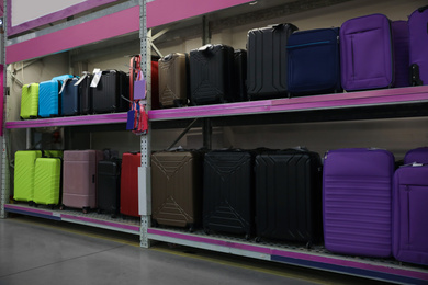 Photo of Many modern suitcases on shelves at wholesale market