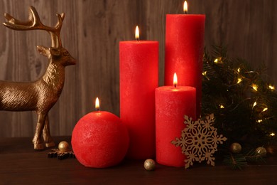 Beautiful burning candles with Christmas decor on wooden table