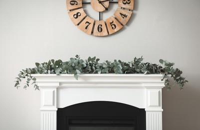 Beautiful garland with eucalyptus branches on mantelpiece in room
