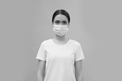 Woman wearing medical face mask on light background. Black and white photography