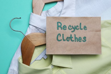 Recycling concept. Clothes and card with phrase on turquoise background, closeup