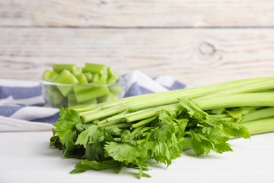 Photo of Fresh ripe green celery on white wooden table, closeup. Space for text