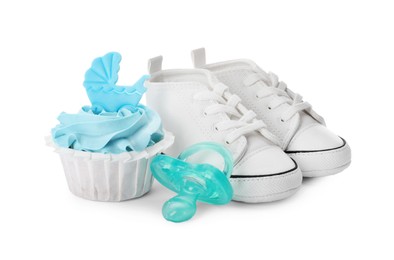 Baby shower cupcake with light blue cream near shoes and pacifier on white background