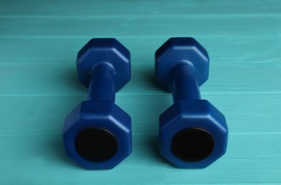 Photo of Blue vinyl dumbbells on turquoise wooden table