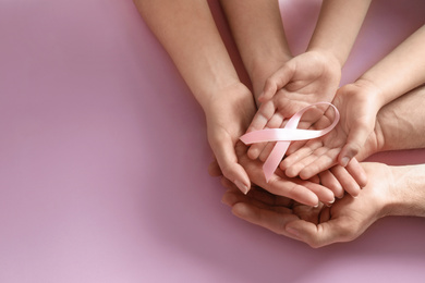 Photo of Family holding pink ribbon on color background, top view with space for text. Breast cancer awareness