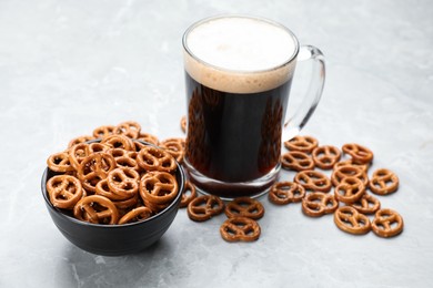 Delicious pretzel crackers and glass of beer on light grey table