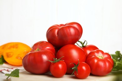 Pile of different ripe tomatoes on table