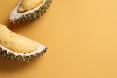 Pieces of fresh ripe durian on orange background, flat lay. Space for text