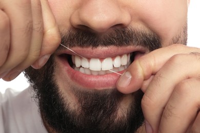 Man flossing his teeth on white background, closeup. Dental care