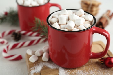Hot drink with marshmallows in red cup on white table