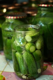 Pickling jars with fresh cucumbers on table, closeup